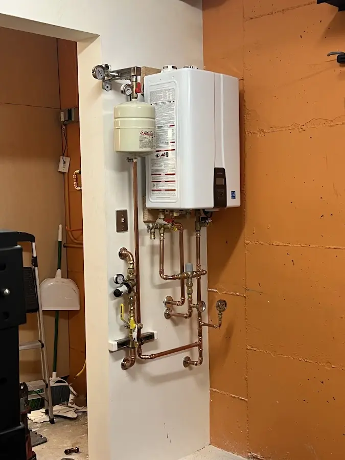 Plumbing technician inspecting water heater connections in Riverdale